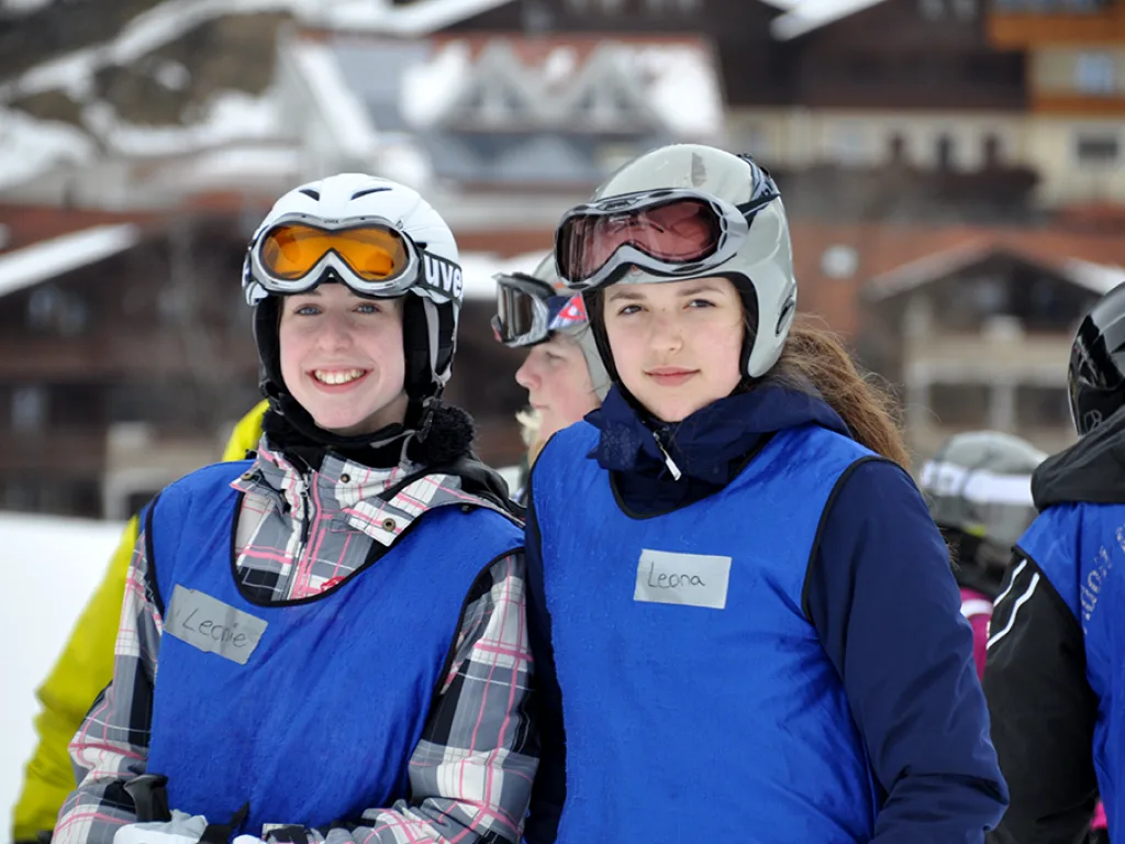 Zwei Jugendliche mit Helm und Skibrille lachen in die Kamera.